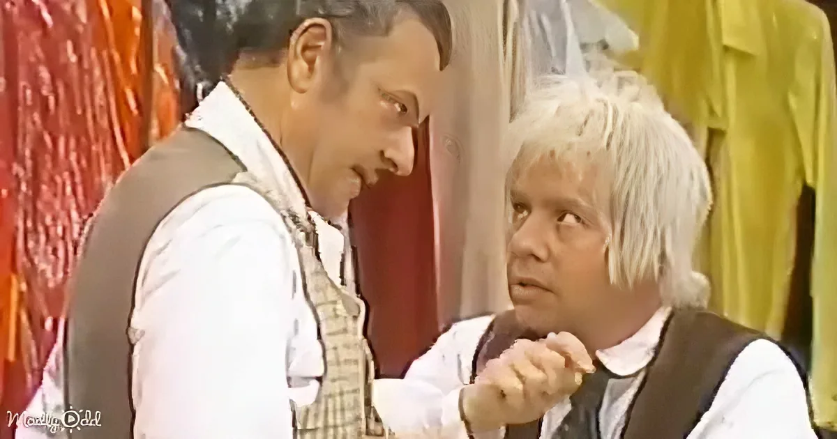 A man with white hair and a vest is holding a cane, looking up at another man in a vest and white shirt.