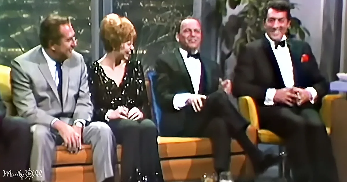 Four people in formal attire sit on yellow chairs, smiling and engaged in conversation.