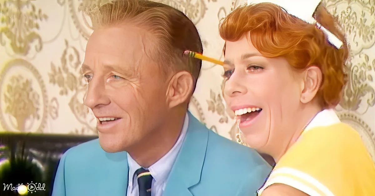 A man in a blue suit and a woman with red hair and a pencil in her mouth are interacting in a humorous scene.