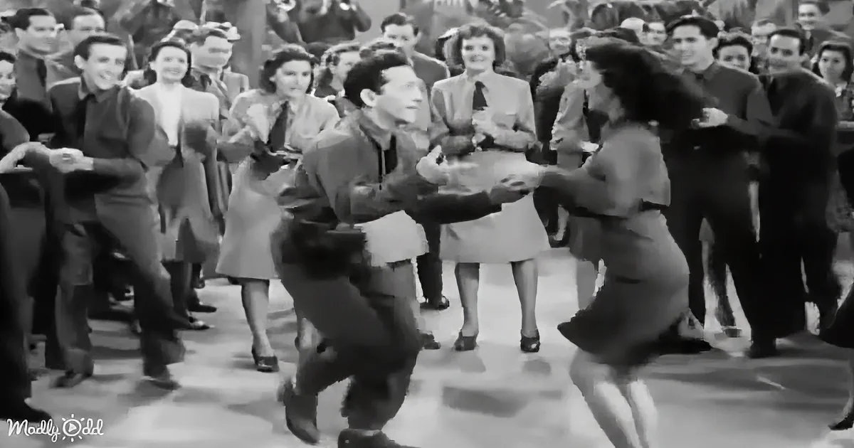 A man and woman are dancing in a crowded room, surrounded by onlookers.