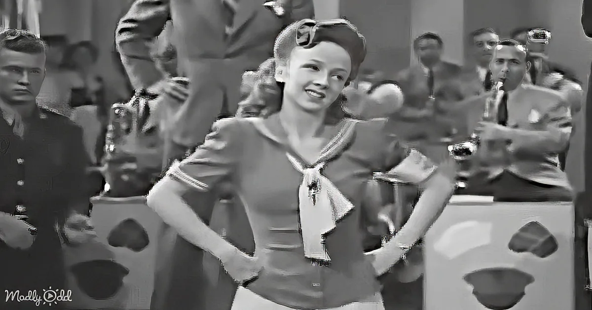 A smiling woman in a sailor-style outfit dances in front of a band.