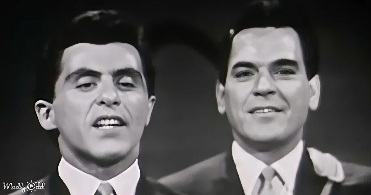 Two men in suits and ties, one singing, both smiling, in a black-and-white image.