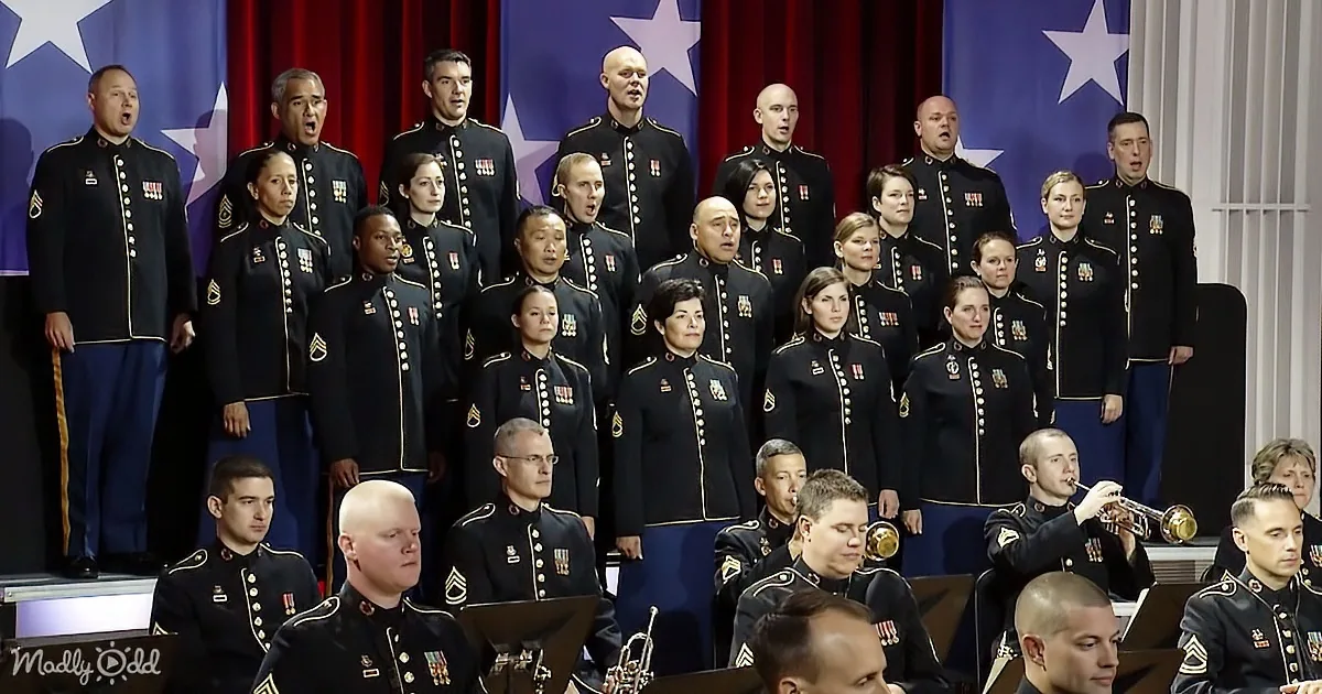 A military choir and band in uniform perform in front of American flags.
