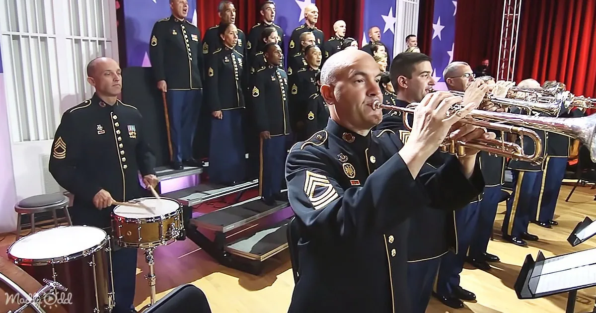 A man in military uniform plays a trumpet in front of a choir and drummers.