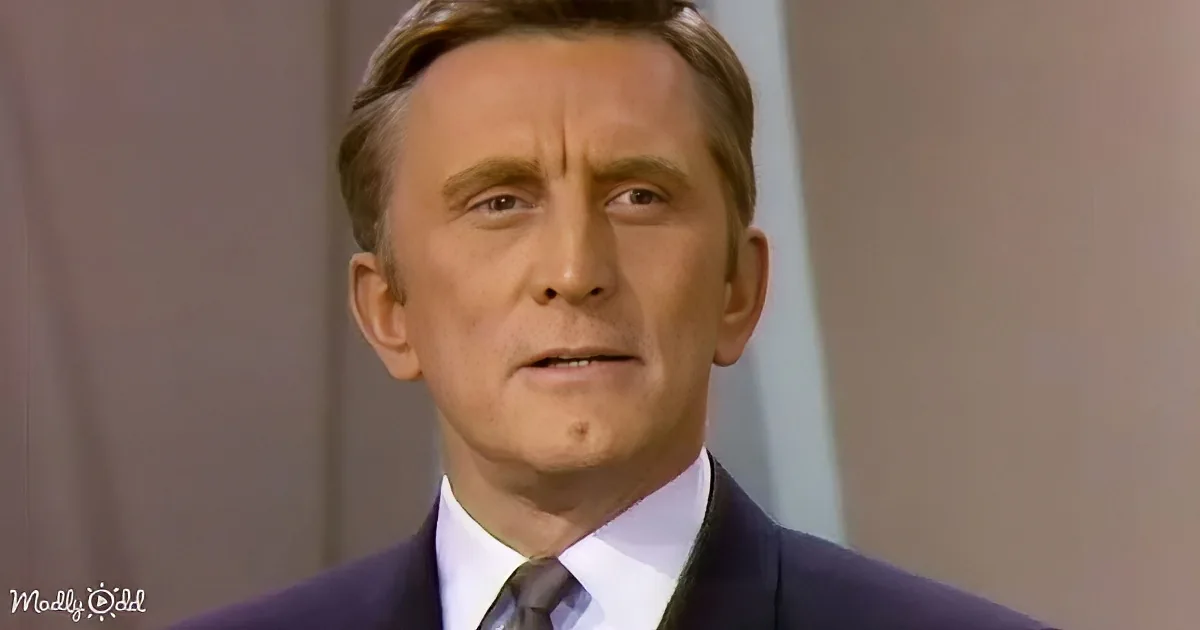 A man in a suit and tie looks to the side with a serious expression.