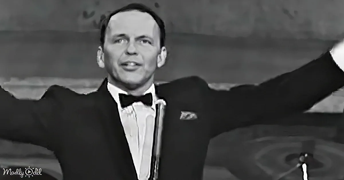 Frank Sinatra in a tuxedo with arms outstretched, smiling, and holding a microphone.