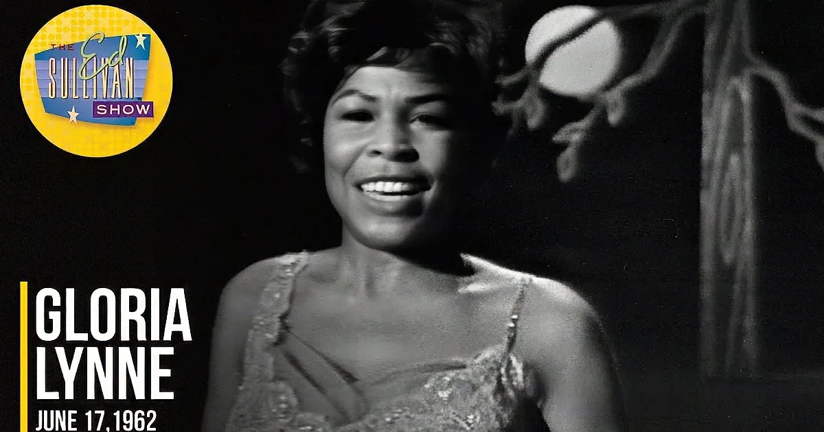 A woman with curly hair smiles upward in a black-and-white image.