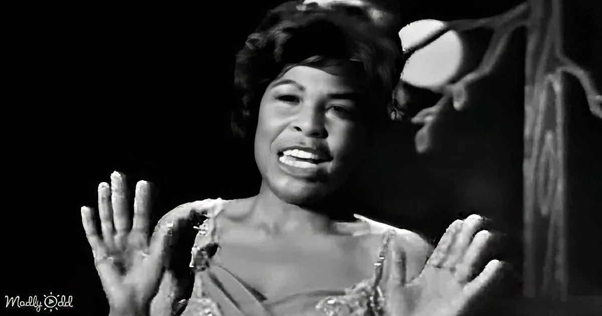 A woman with a joyful expression, hands raised, wearing a light-colored dress, in a black-and-white image.