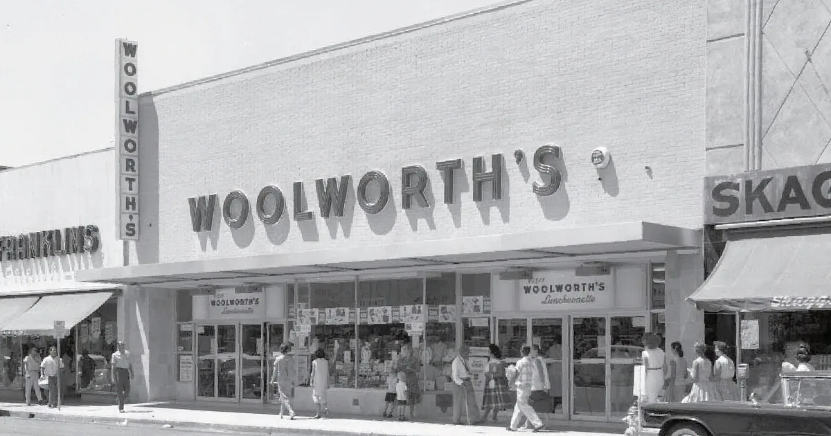 Woolworth's store facade with people and vintage cars in front.