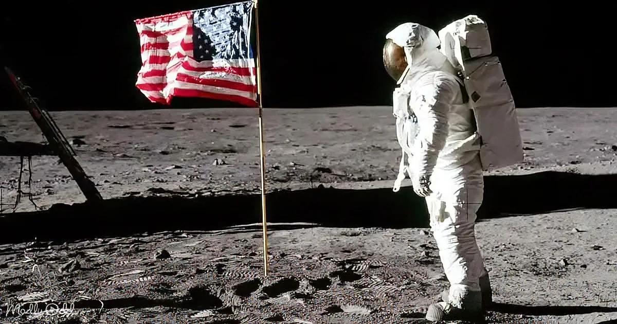 A lone astronaut stands on the moon next to an American flag.