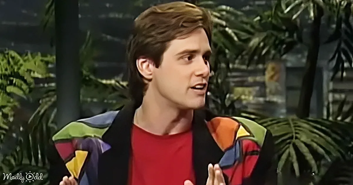 A person in a colorful jacket and red shirt gestures while speaking, with a tropical backdrop.