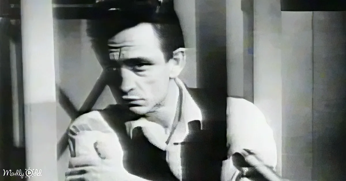 A man in a suit, holding a cigarette, with a serious expression, in a monochrome setting.