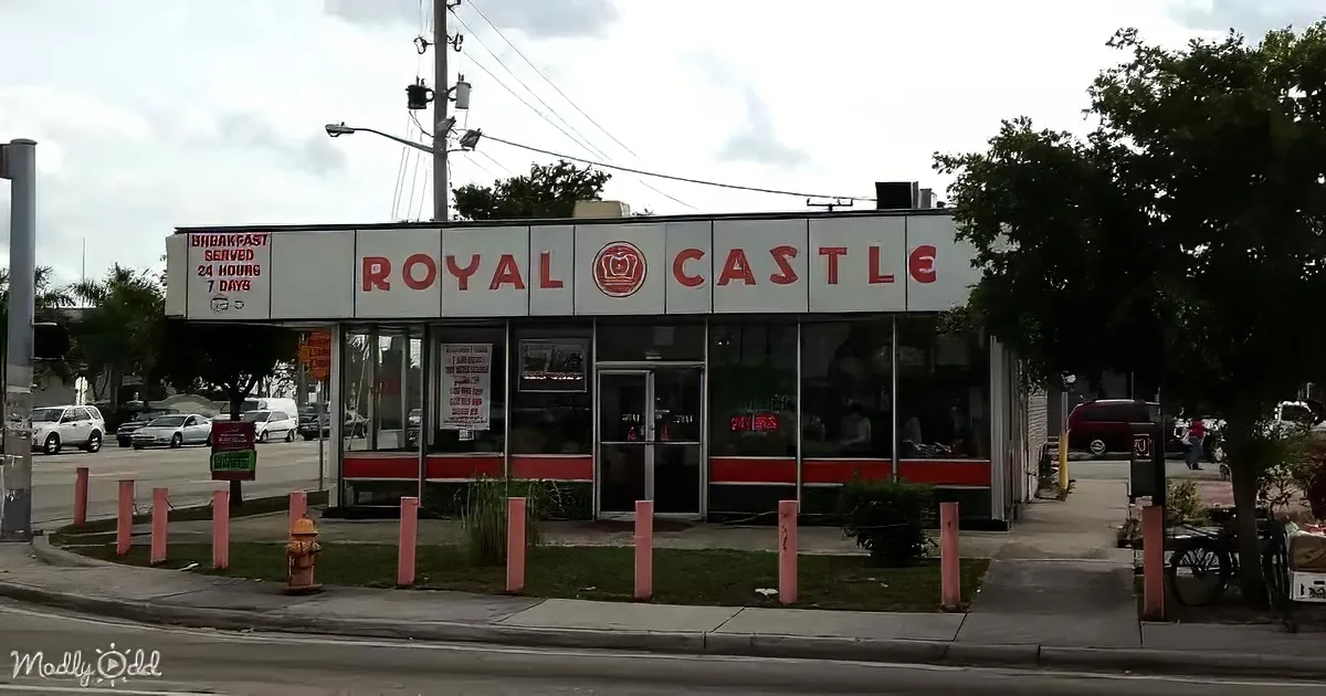 Royal Castle diner with "Breakfast Served 24 Hours 7 Days" sign, red and white exterior, open doors, and parked cars nearby.