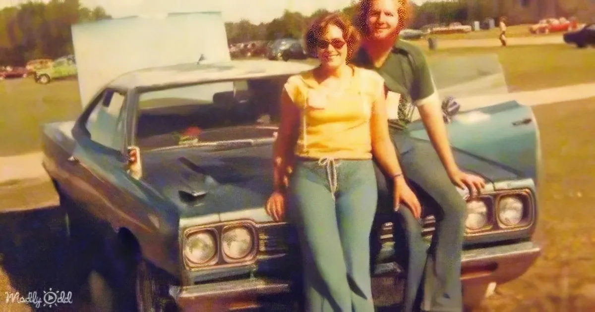 A man and woman stand beside a teal vintage car, smiling at the camera.