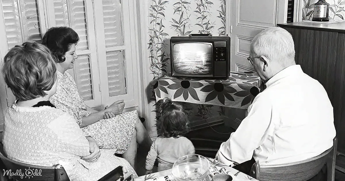 A family gathers around a vintage TV, watching a program together in a cozy living room.