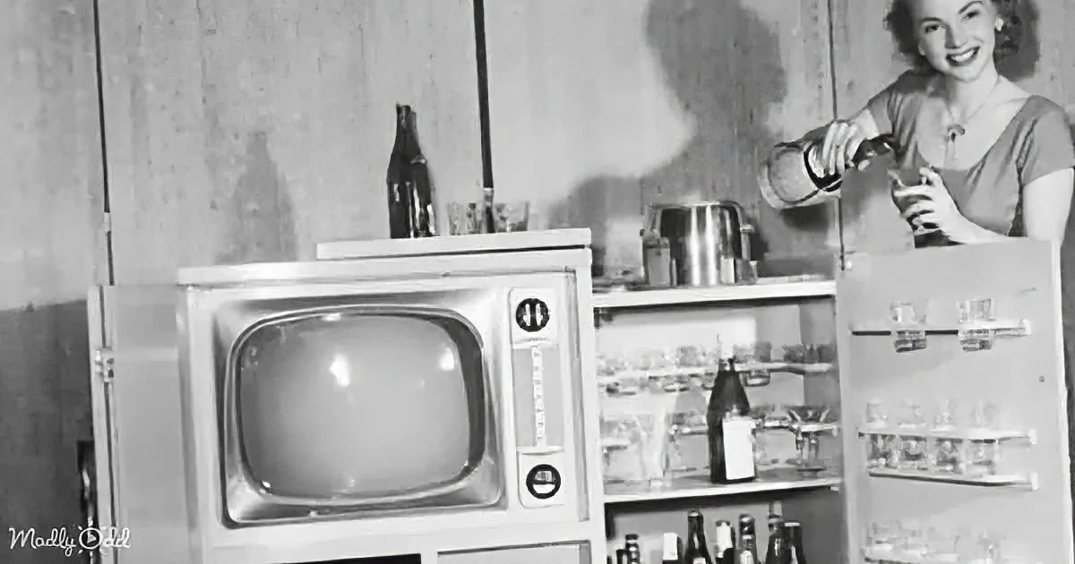 A woman pours a drink in a retro kitchen with a vintage television and refrigerator.