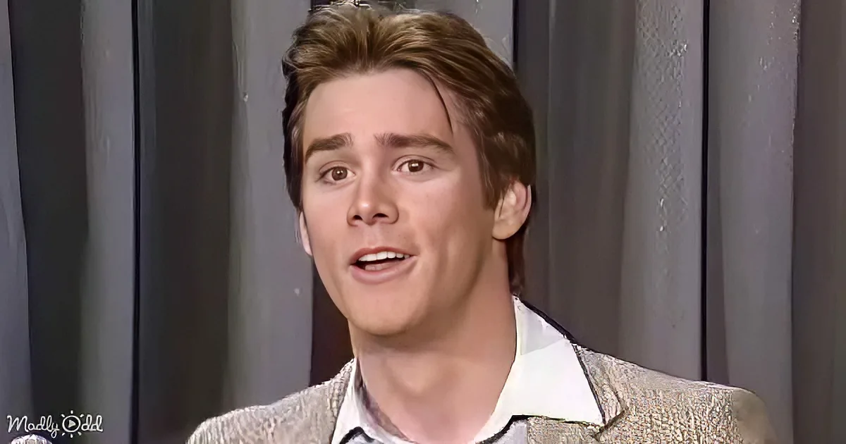 A man with light brown hair, wearing a patterned blazer and white shirt, appears to be speaking or reacting to something.