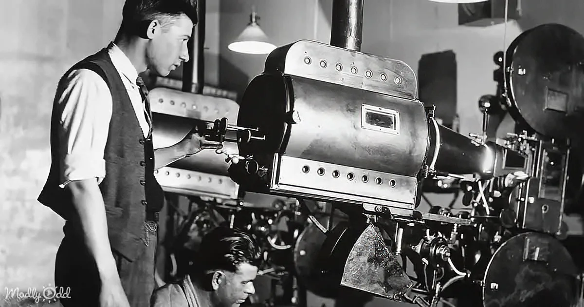 A man in a vest operates a large, intricate machine in a workshop setting.