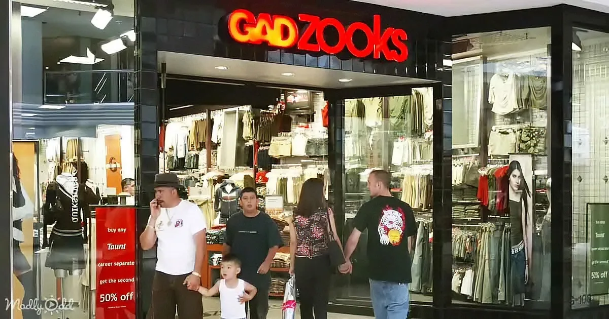 A family stands outside Gadzooks store, a clothing shop, with a sign offering a second item at 50% off.