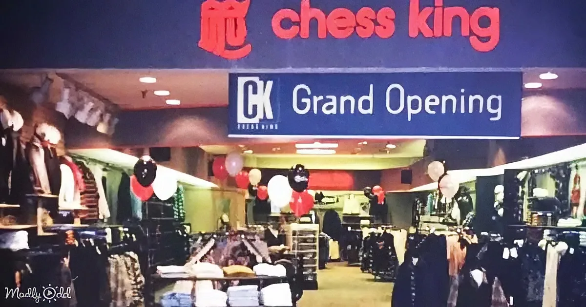 A grand opening sign for Chess King store with balloons and clothing racks inside.