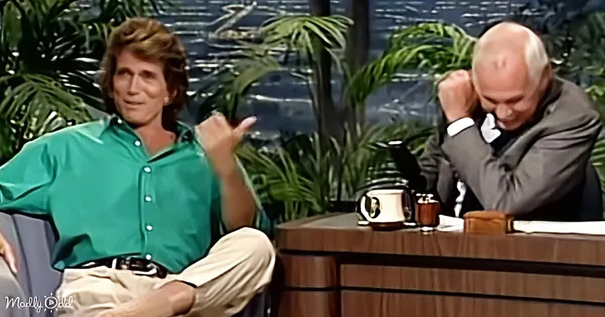 A man in a green shirt gestures animatedly while sitting on a talk show set, with another man in a suit appearing distressed.