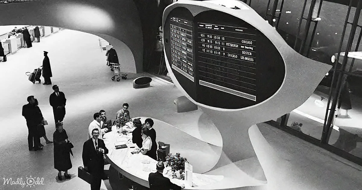 A futuristic airport terminal with a large, curved, modernist flight information display.