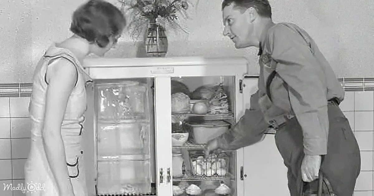 A man and woman are interacting with a vintage refrigerator, showcasing its contents.