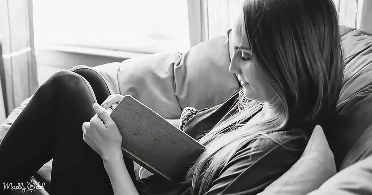 A woman lounging on a couch reads a book, her legs crossed, in a serene indoor setting.