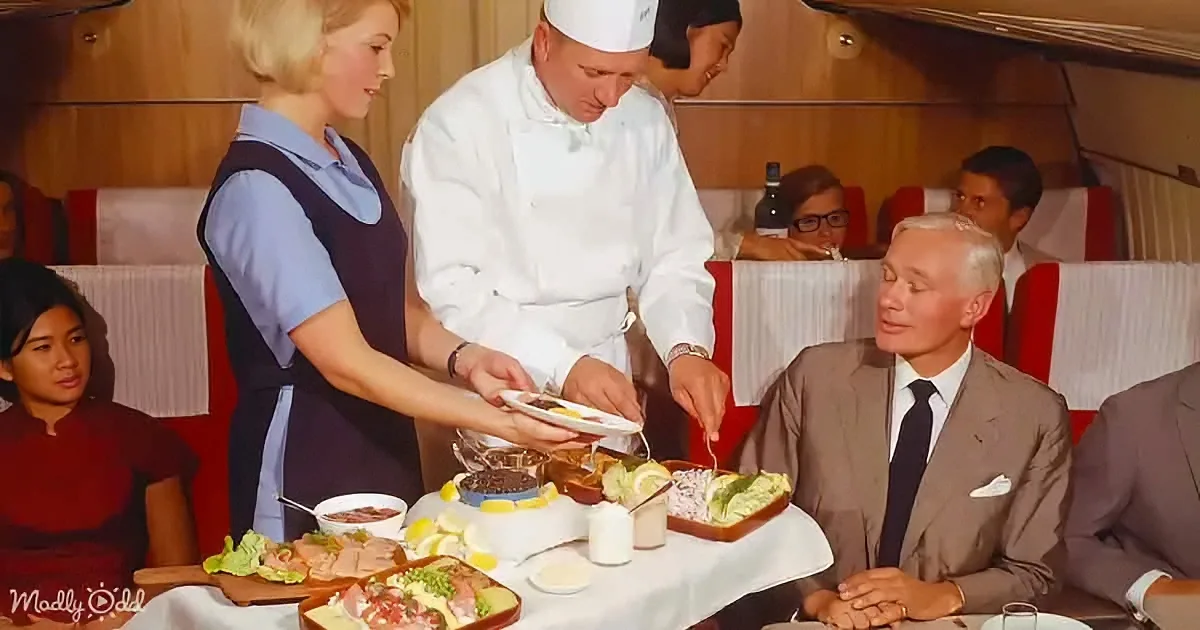 A chef serves food to a man in a suit at a dining table with various dishes.