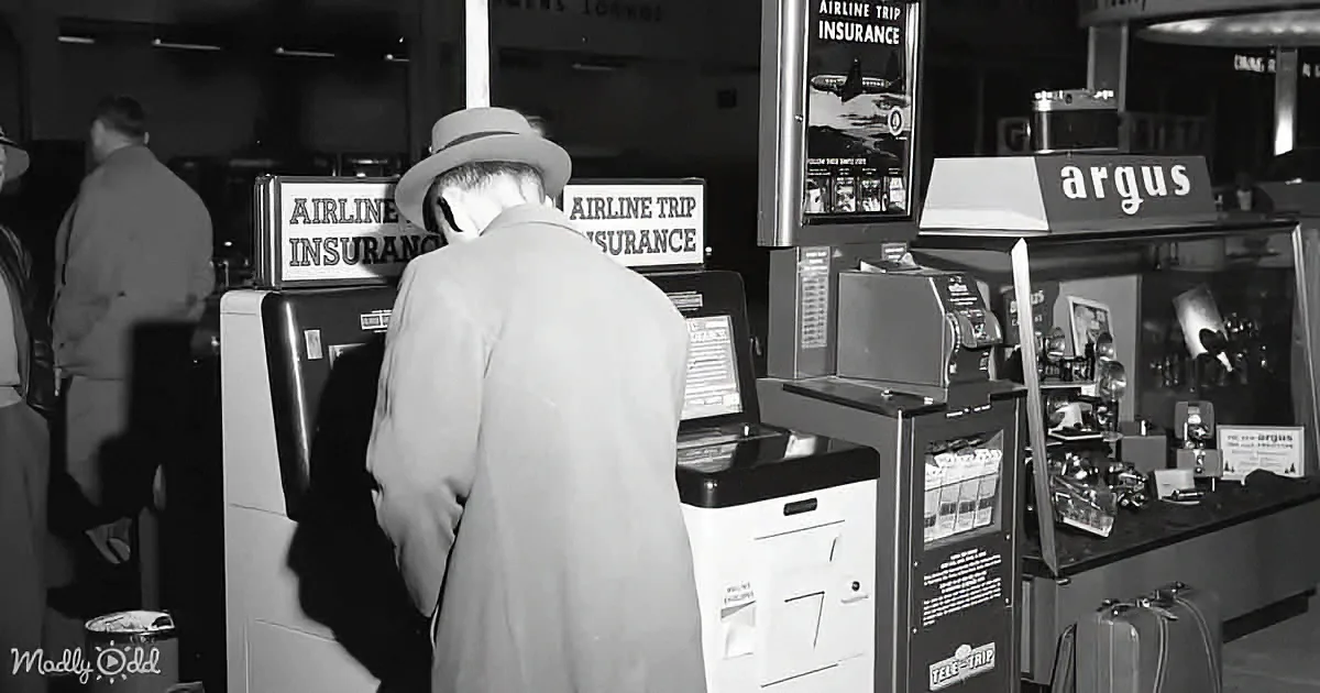 A man in a hat stands at an airline insurance kiosk, looking at a display.