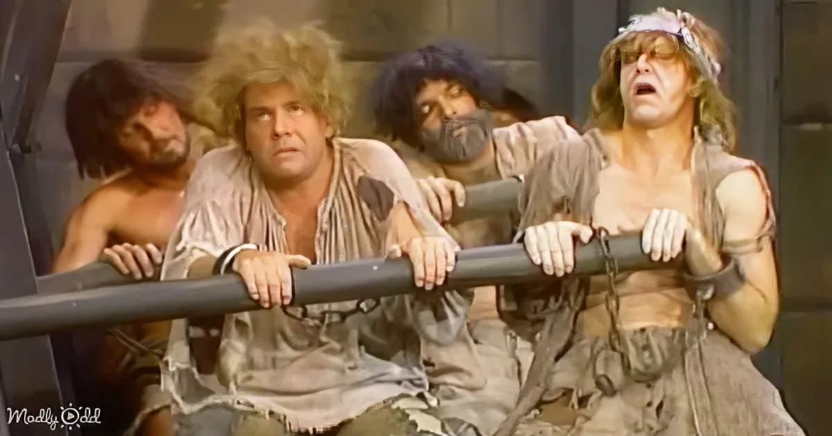 Three men in medieval attire, bound and gagged, lean on a metal railing, appearing distressed.