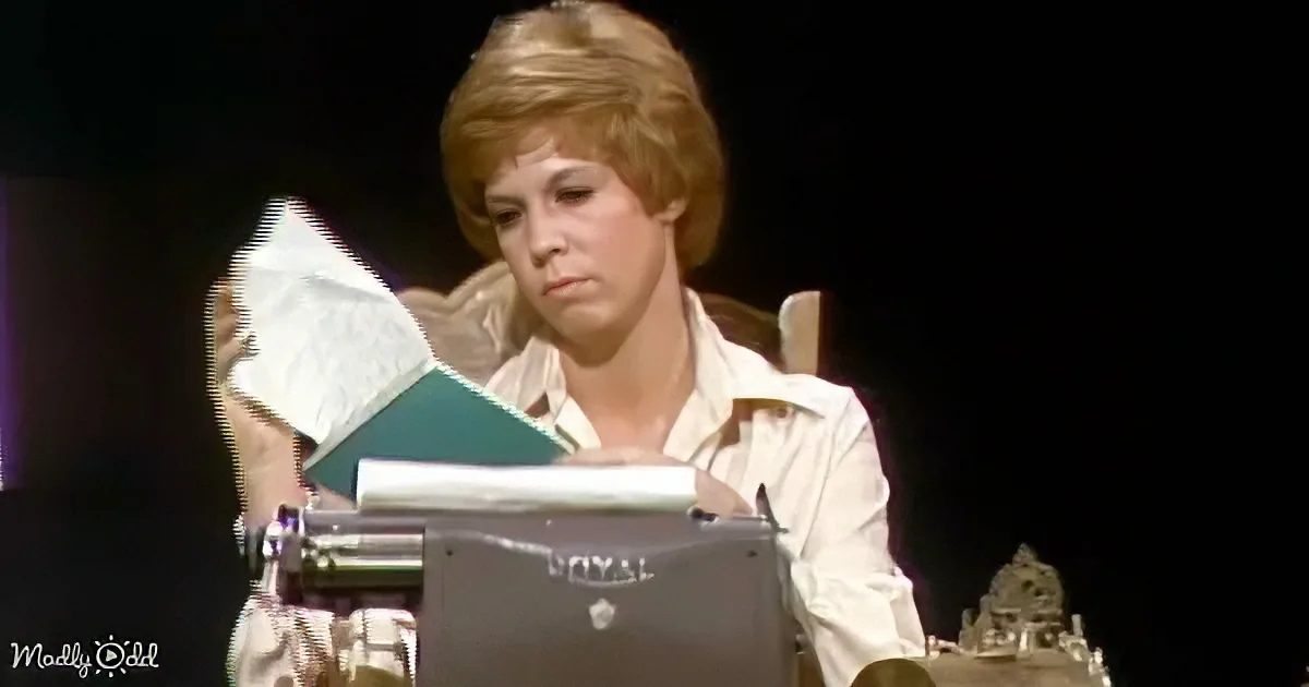 A woman in a white shirt is typing on a Royal typewriter, holding a piece of paper.