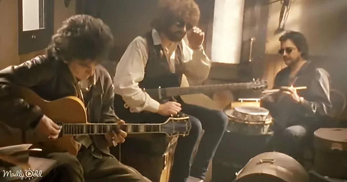 A musician in a leather jacket plays guitar while another in a white shirt and vest plays a bass, with a drummer in the...