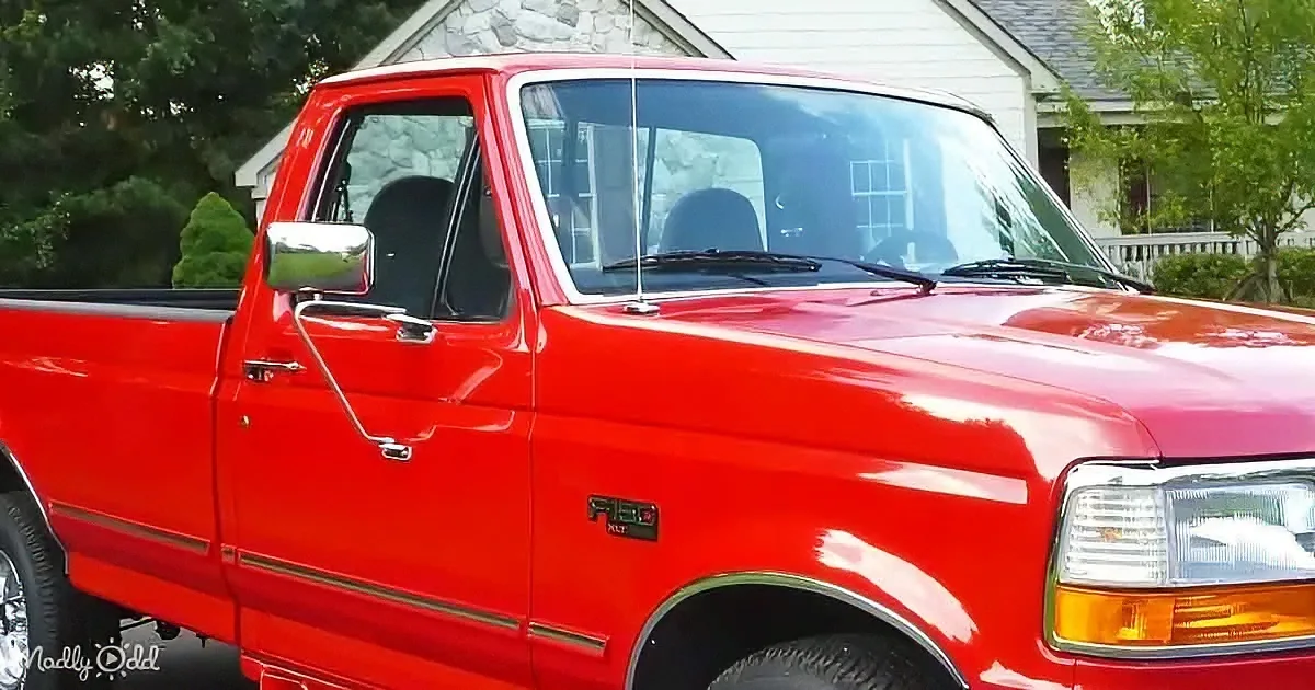 A shiny red Ford F-150 pickup truck is parked in front of a house with a stone facade.