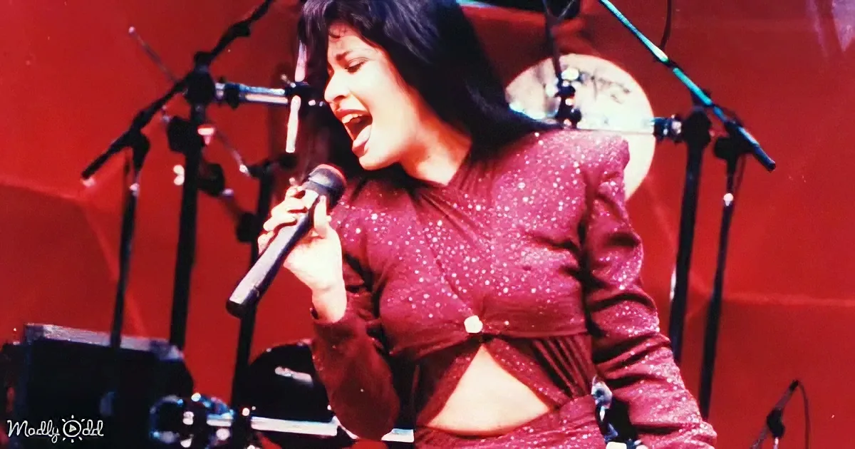 A woman in a sparkly red outfit sings into a microphone on stage, surrounded by microphones and equipment.