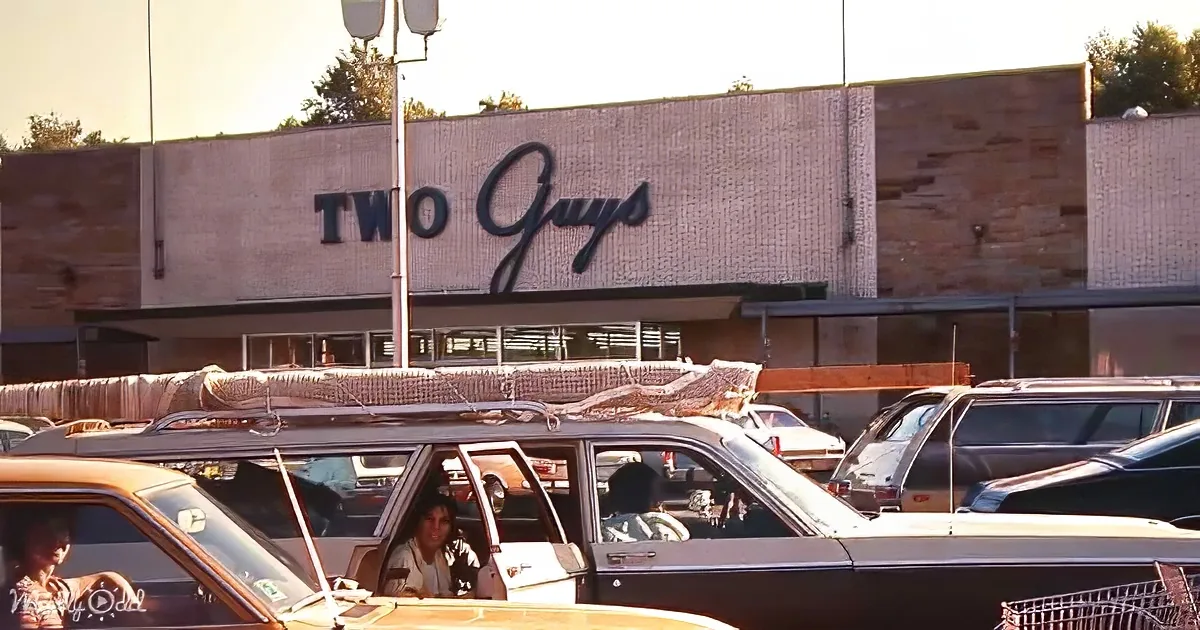 Cars parked in front of a building with "Two Guys" sign, people inside, sunny day.