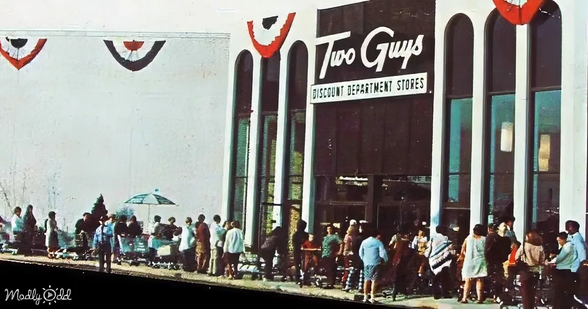 People gather outside a "Two Guys Discount Department Stores" building with festive decorations.