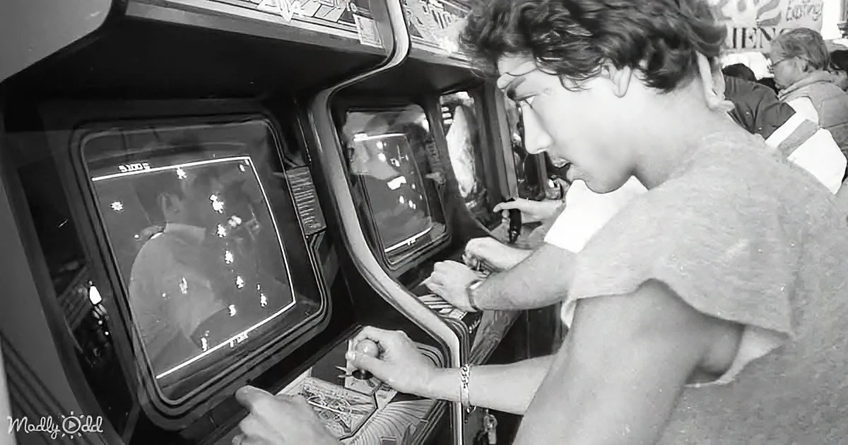 A person intensely plays an arcade game, gripping the controls with focus.