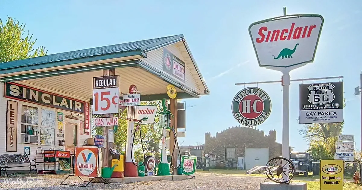 A vintage Sinclair gas station with retro signs, pumps, and a dinosaur logo stands under a clear blue sky.