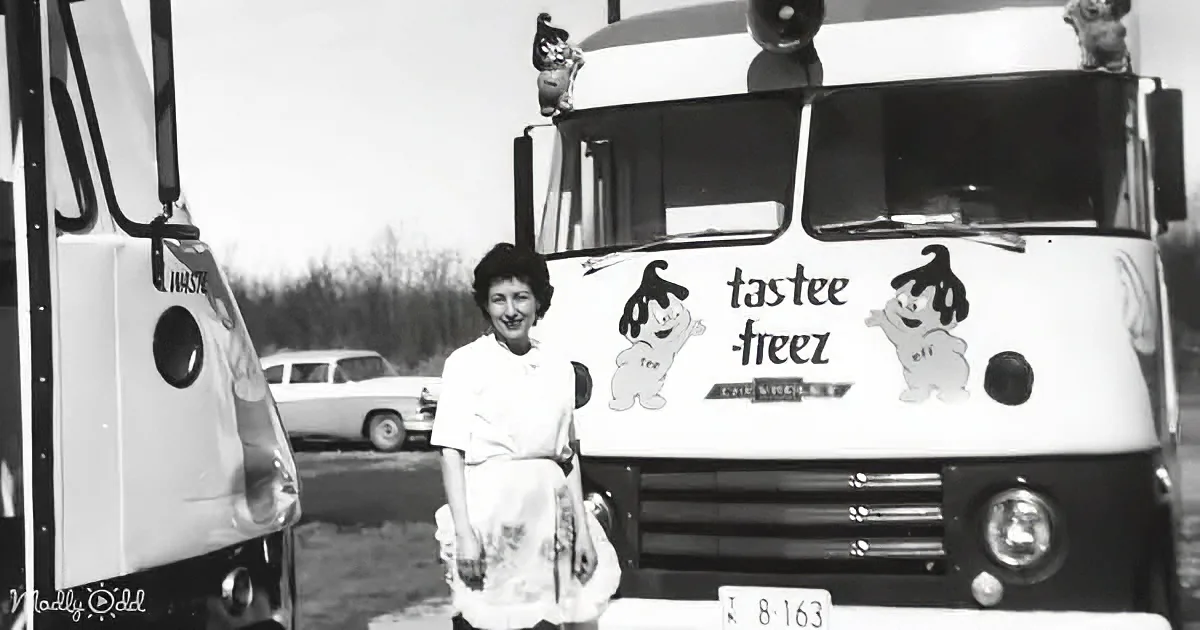 A woman stands in front of a vintage Tastee-Freeze ice cream truck, smiling.