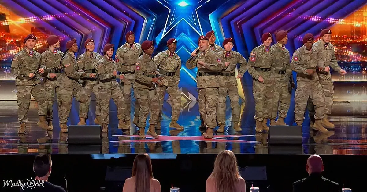 A group of soldiers in camouflage uniforms performs on a brightly lit stage.