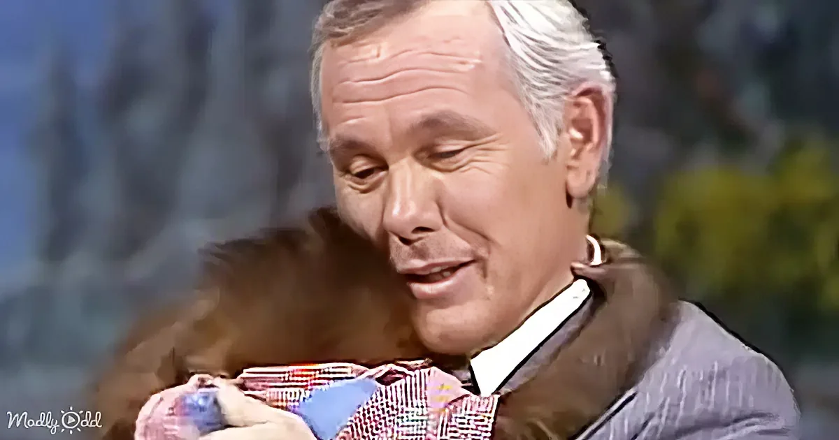 A man in a suit holds a colorful object, possibly a tie, with a blurred background.