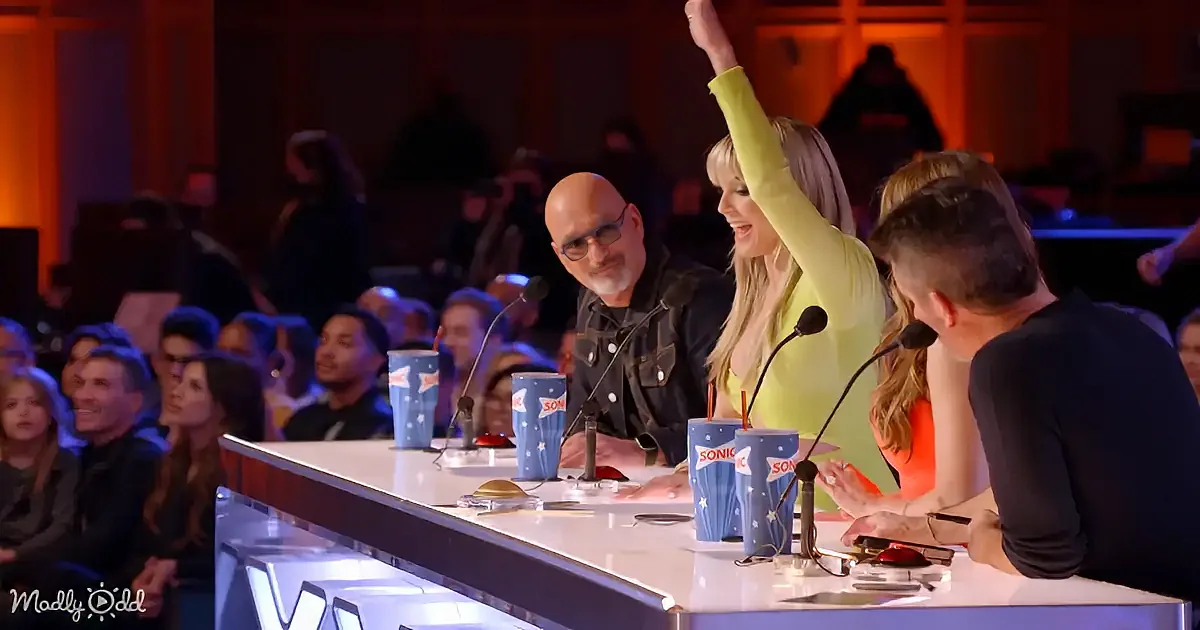 A woman in a bright yellow top raises her arm in excitement at a panel discussion.