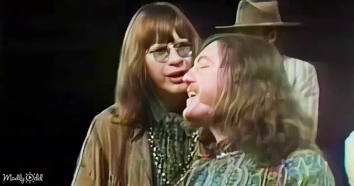 Two individuals, one in a hat, appear to be in a close, emotional embrace, with one person leaning in closely.