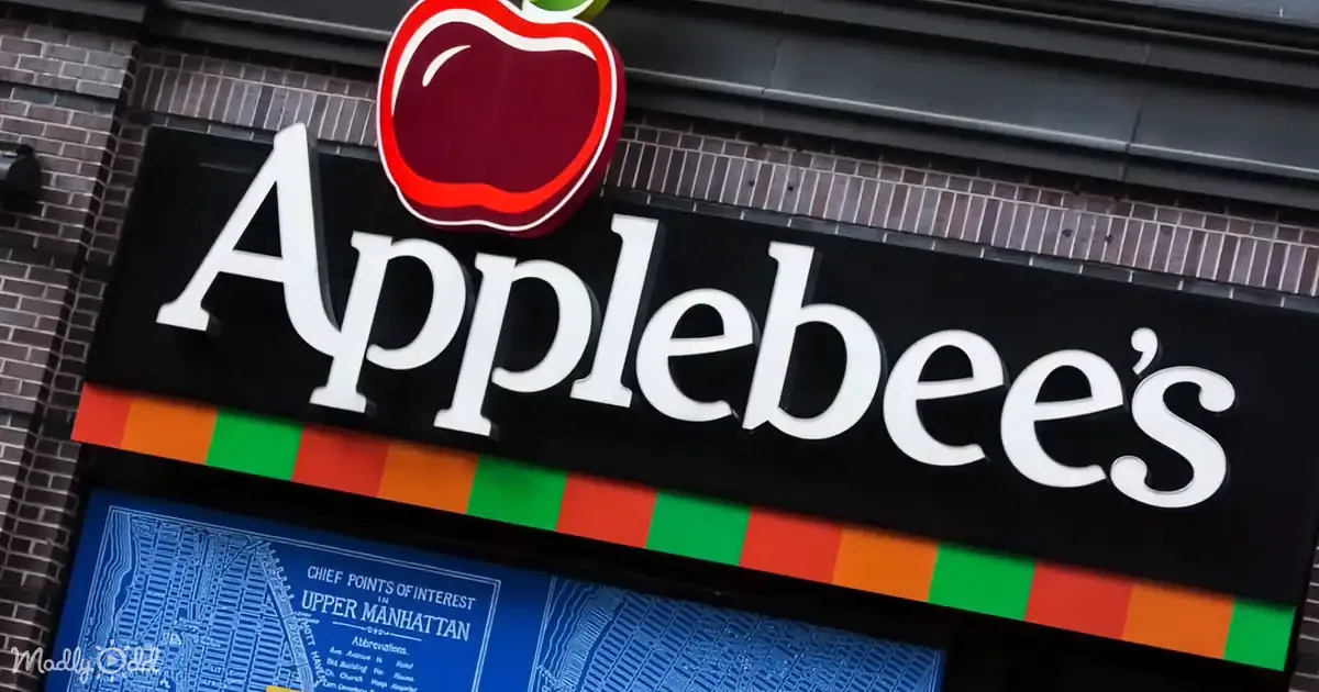 A colorful Applebee's sign with a red apple logo and a brick building background.