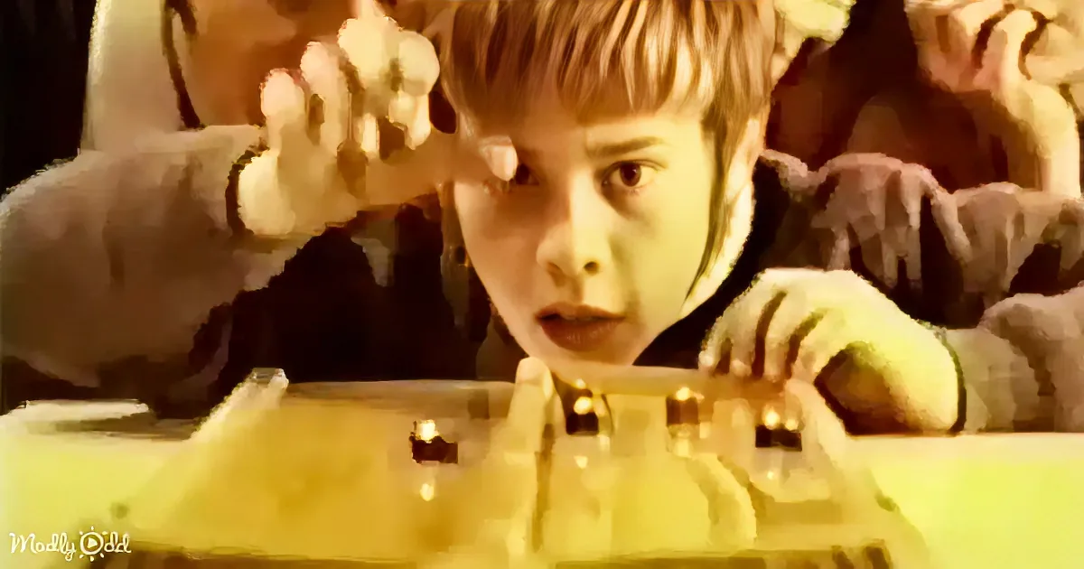 A young boy with blonde hair leans forward, intently focused on a small object in front of him.