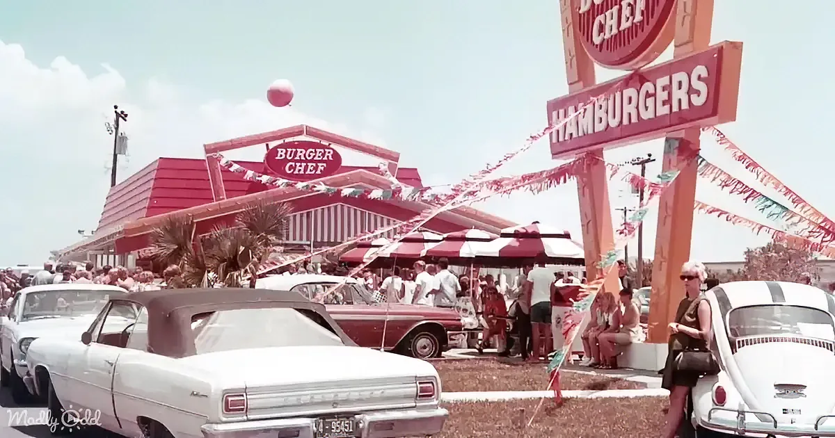 A Burger Chef restaurant with vintage cars, people, and festive decorations in the foreground.