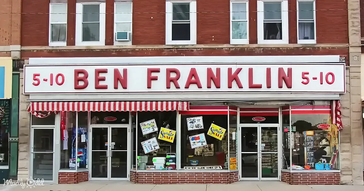 A Ben Franklin 5-10 store with red and white striped awning and various signs in the windows.