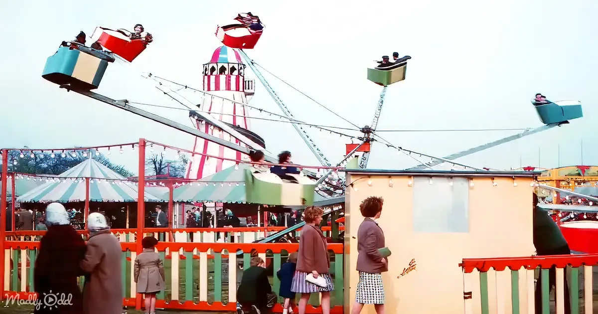 A colorful fairground scene with people watching a ride with swinging seats.