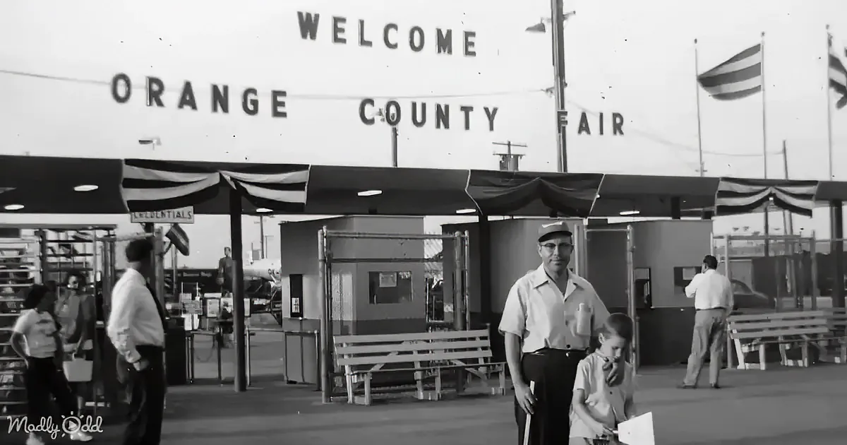 A man and child stand in front of the "Welcome Orange County Fair" sign at the fairgrounds.